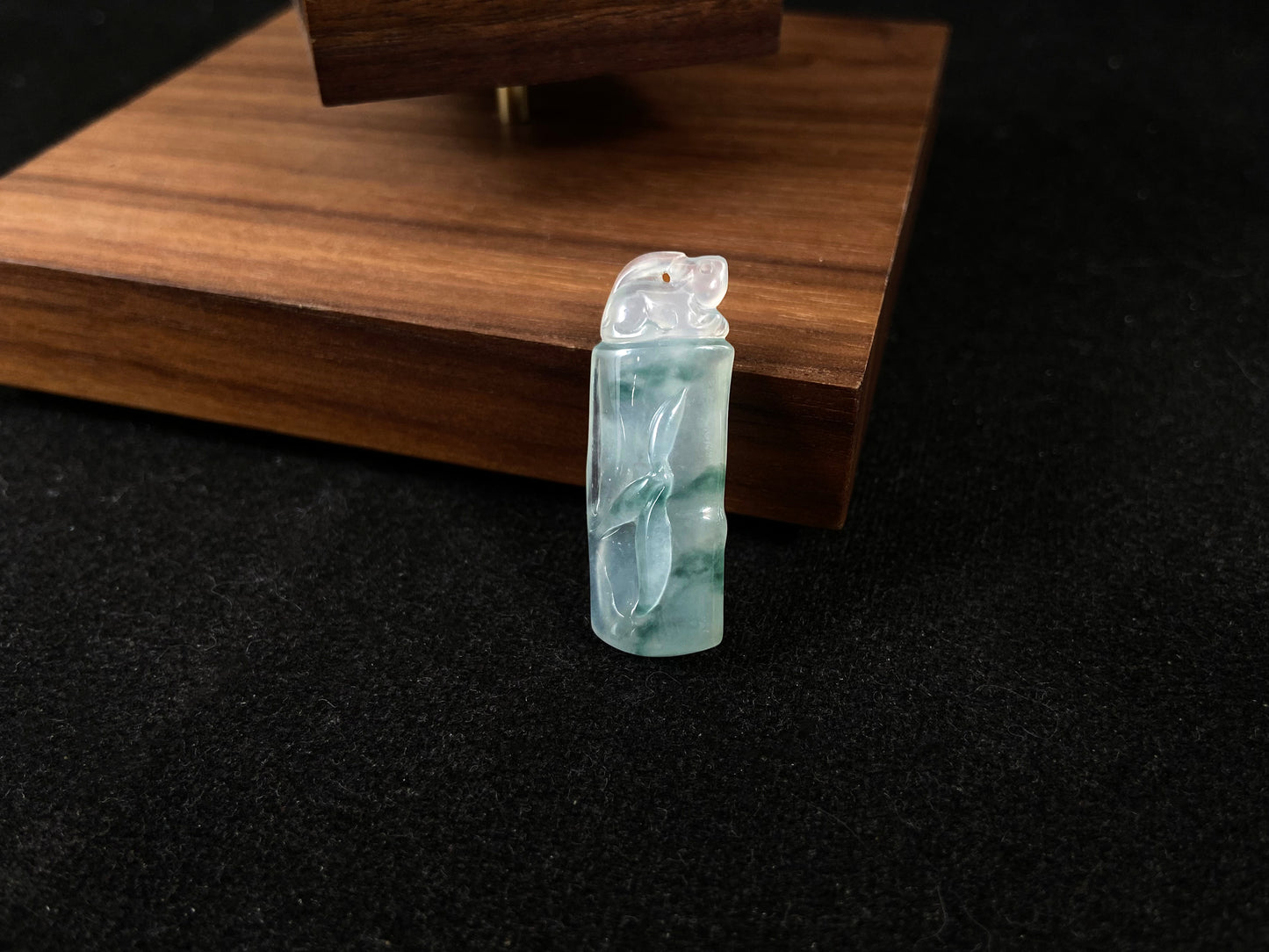 A translucent bamboo shaped jade pendant with floating green accents, symbolizing continual growth and career success.