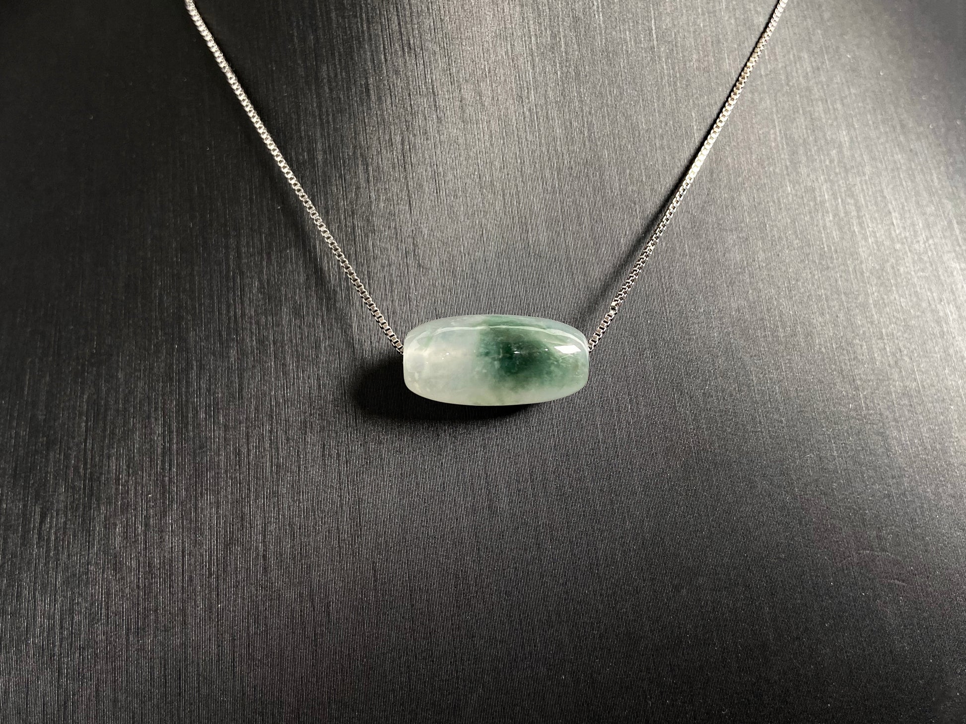 This "Lulutong" jade pendant features a translucent white base adorned with a wisp of green.