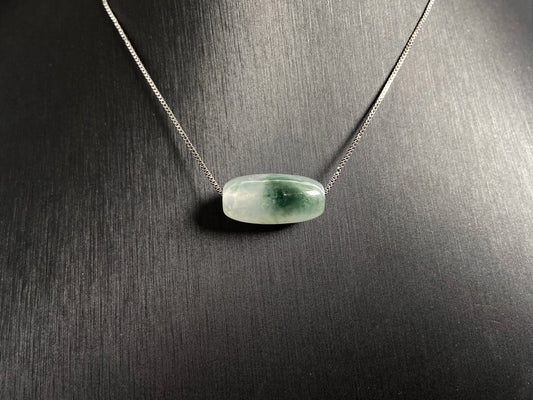 This "Lulutong" jade pendant features a translucent white base adorned with a wisp of green.