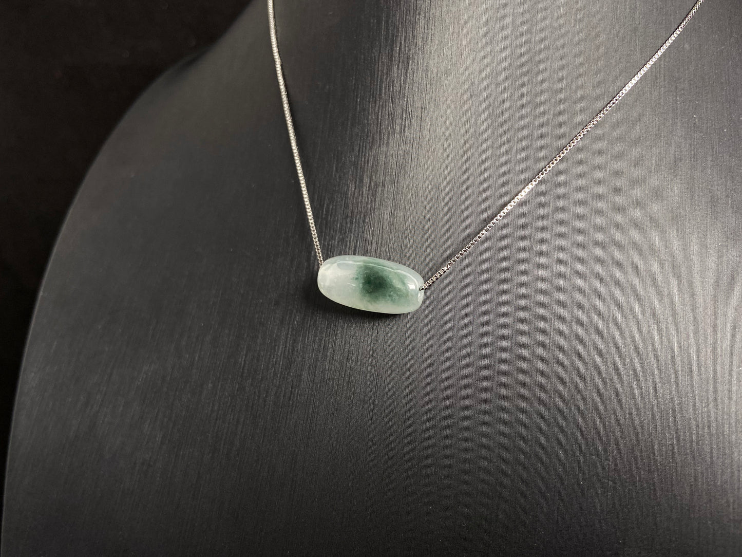 This "Lulutong" jade pendant features a translucent white base adorned with a wisp of green.
