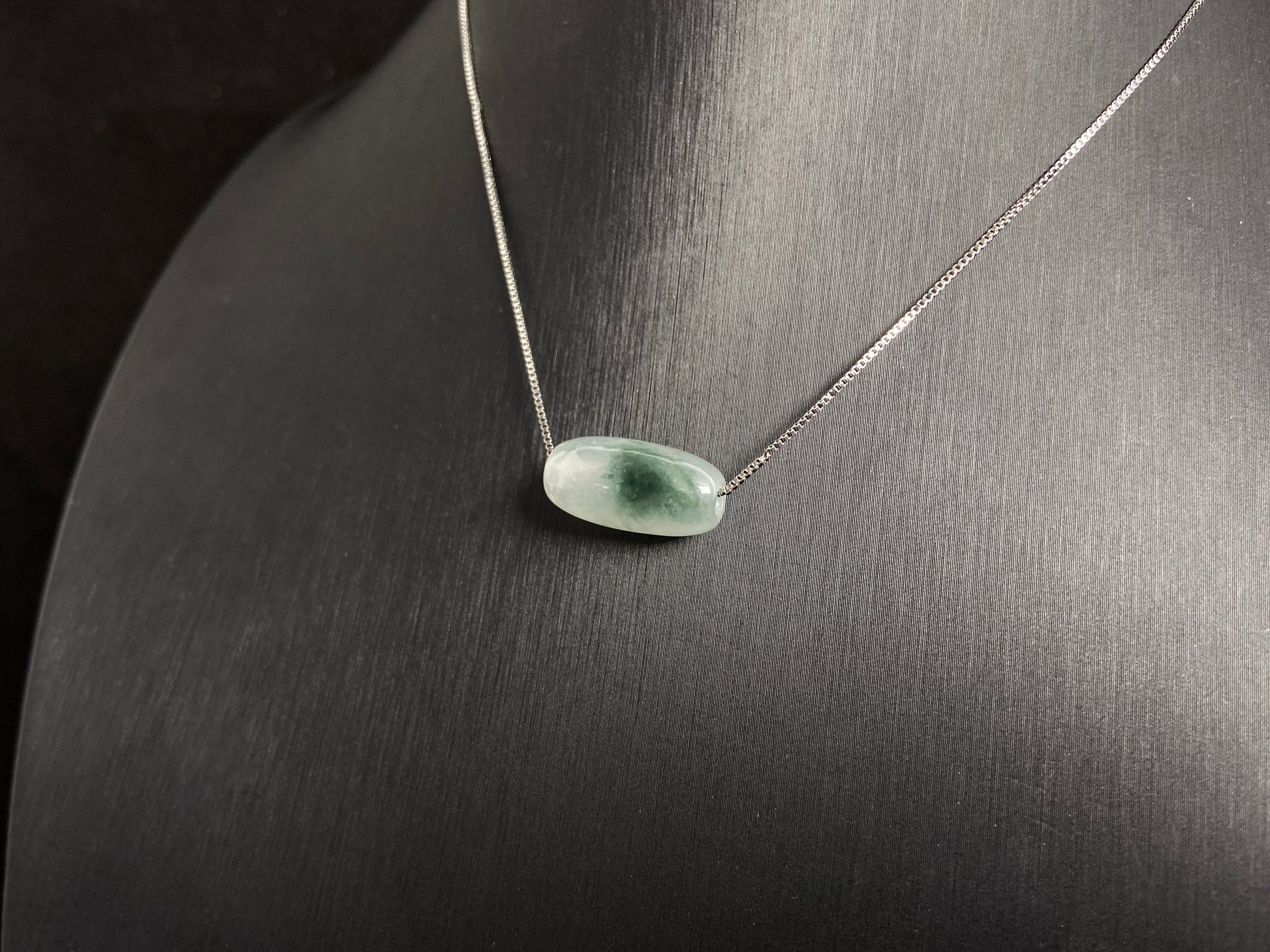 This "Lulutong" jade pendant features a translucent white base adorned with a wisp of green.