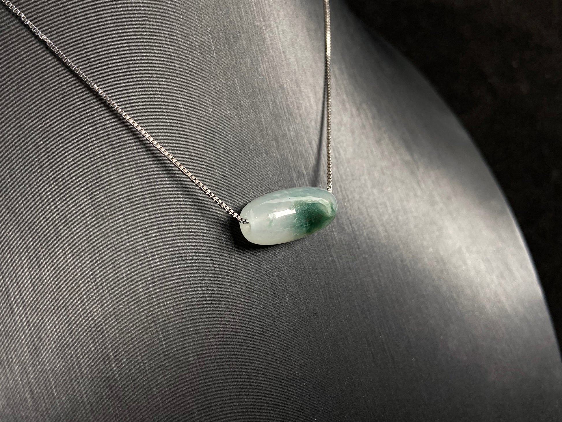 This "Lulutong" jade pendant features a translucent white base adorned with a wisp of green.