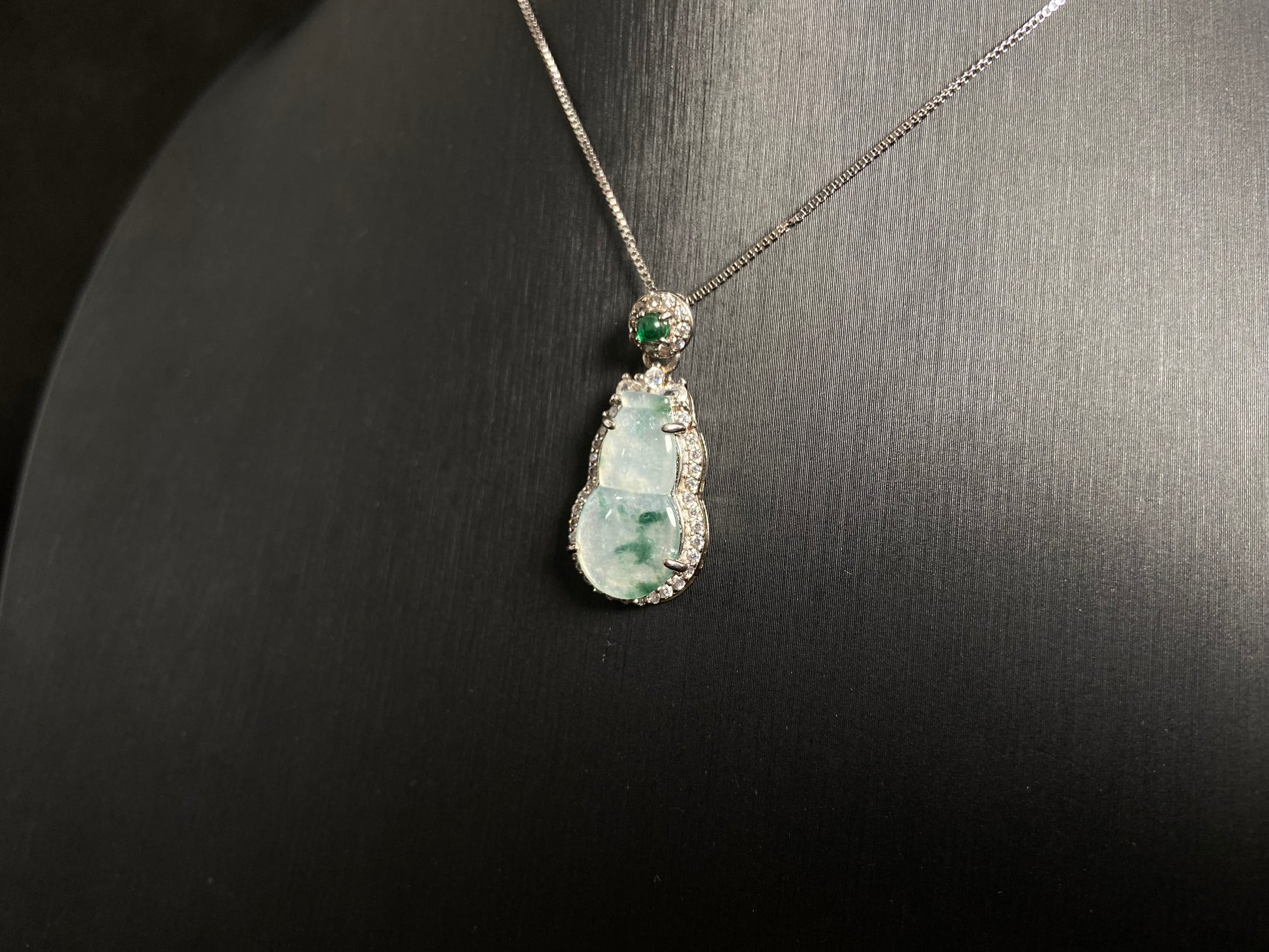This jade pendant features a translucent white Hulu with natural dark green veining, crowned with an imperial green jade bead and set in 925 silver.