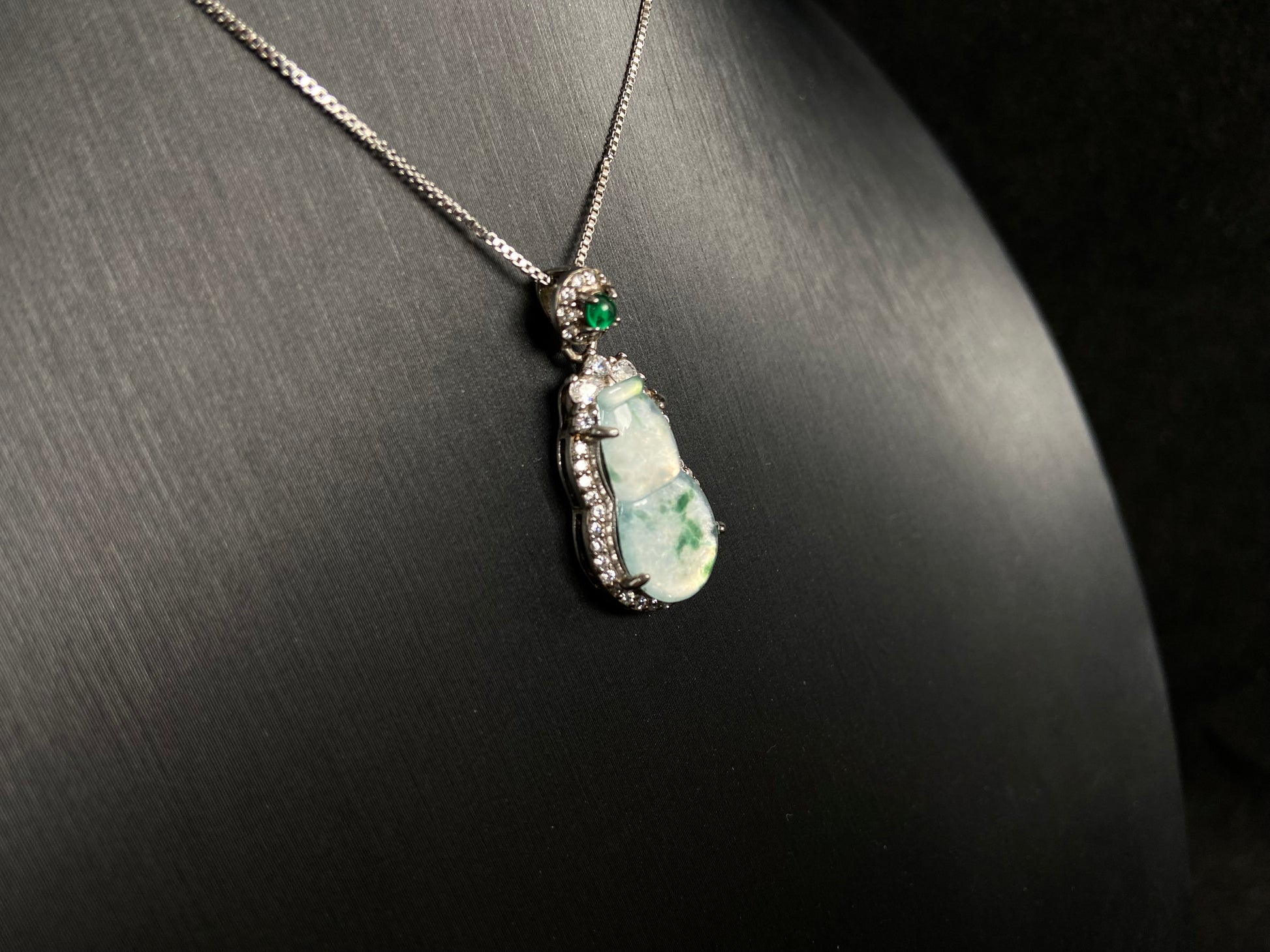 This jade pendant features a translucent white Hulu with natural dark green veining, crowned with an imperial green jade bead and set in 925 silver.