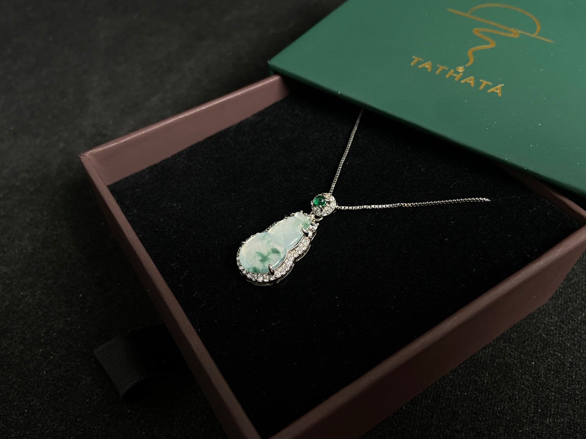 This jade pendant features a translucent white Hulu with natural dark green veining, crowned with an imperial green jade bead and set in 925 silver.