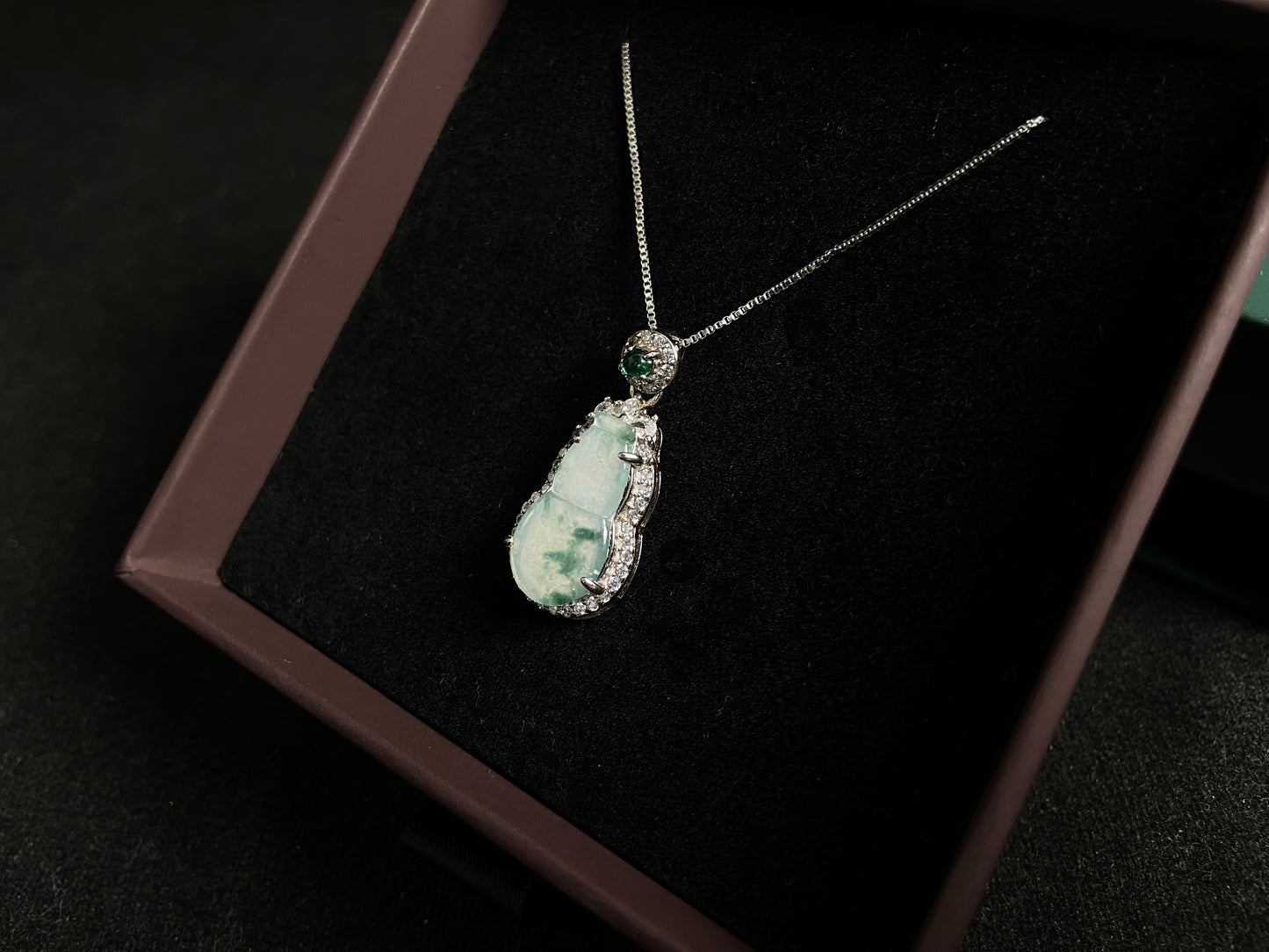 This jade pendant features a translucent white Hulu with natural dark green veining, crowned with an imperial green jade bead and set in 925 silver.