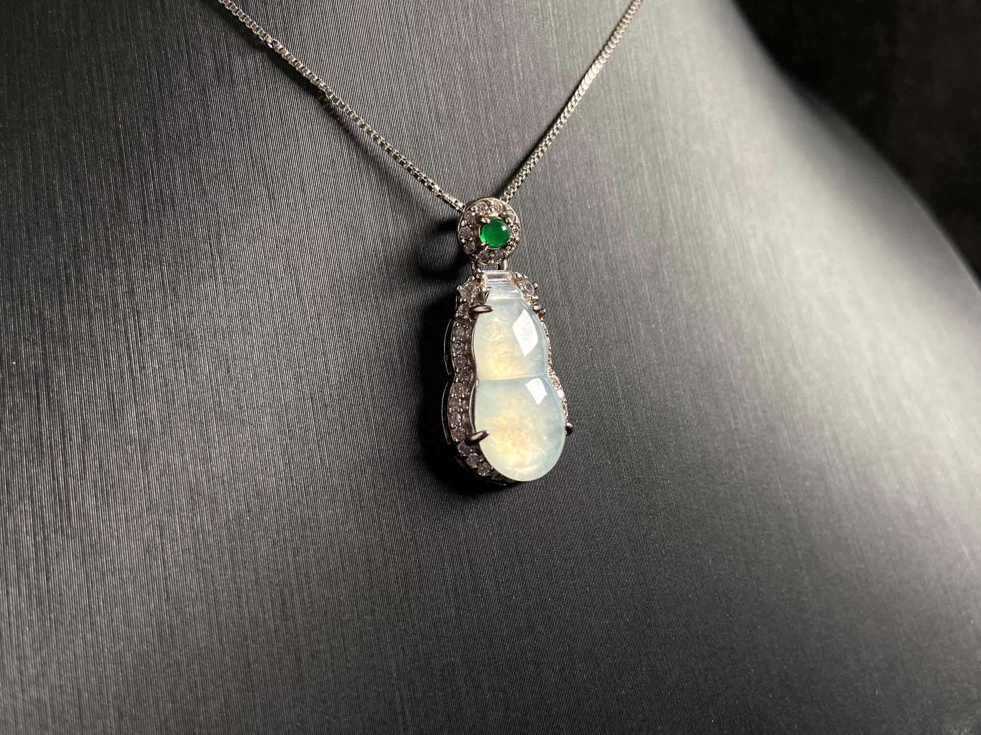 An icy jade gourd pendant with a vibrant green jade bead atop, framed in 925 silver.