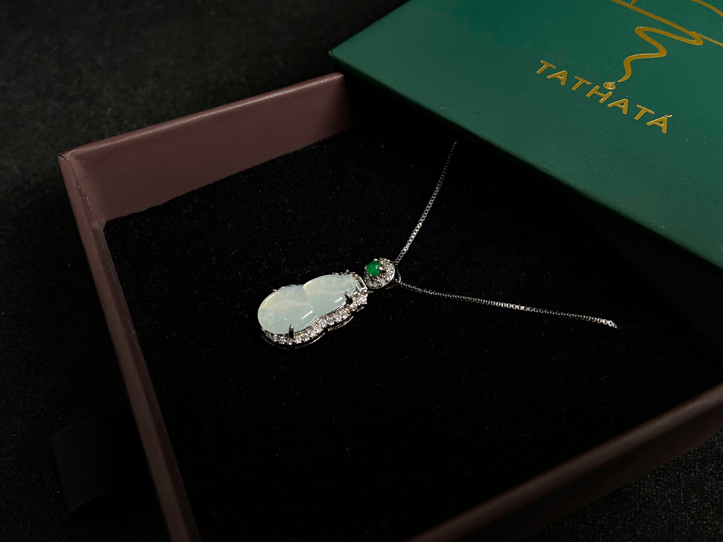 An icy jade gourd pendant with a vibrant green jade bead atop, framed in 925 silver.
