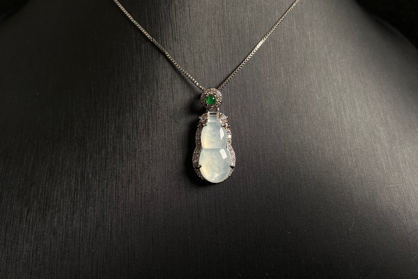 An icy jade gourd pendant with a vibrant green jade bead atop, framed in 925 silver.