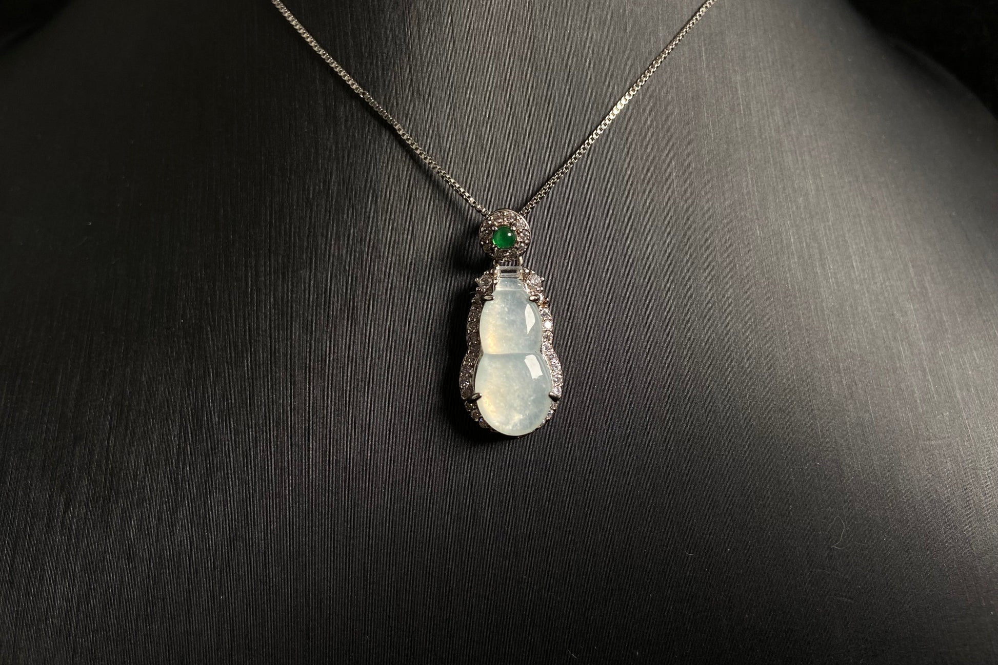 An icy jade gourd pendant with a vibrant green jade bead atop, framed in 925 silver.