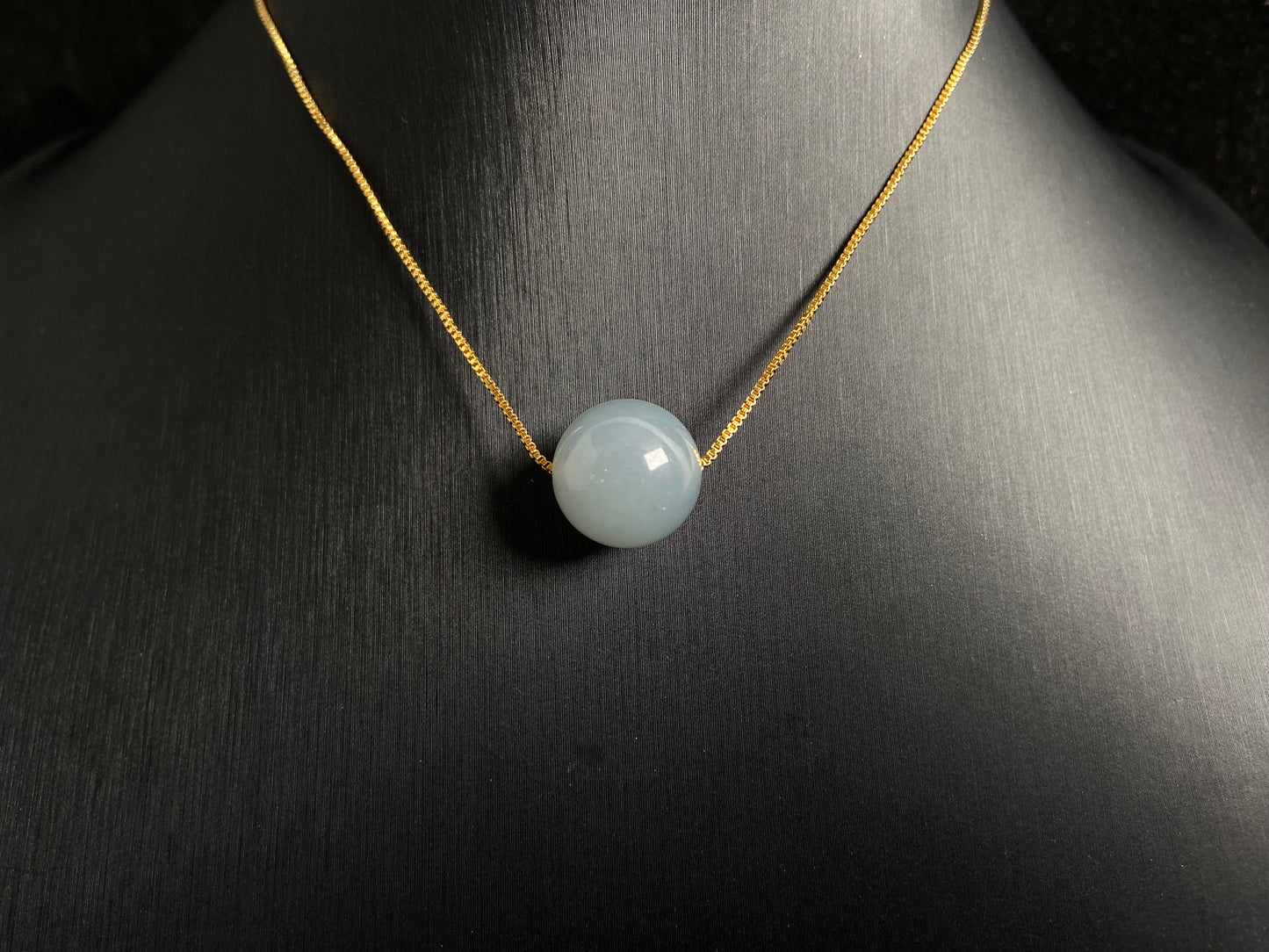 A single milky white jade bead pendant, smooth and luminous.