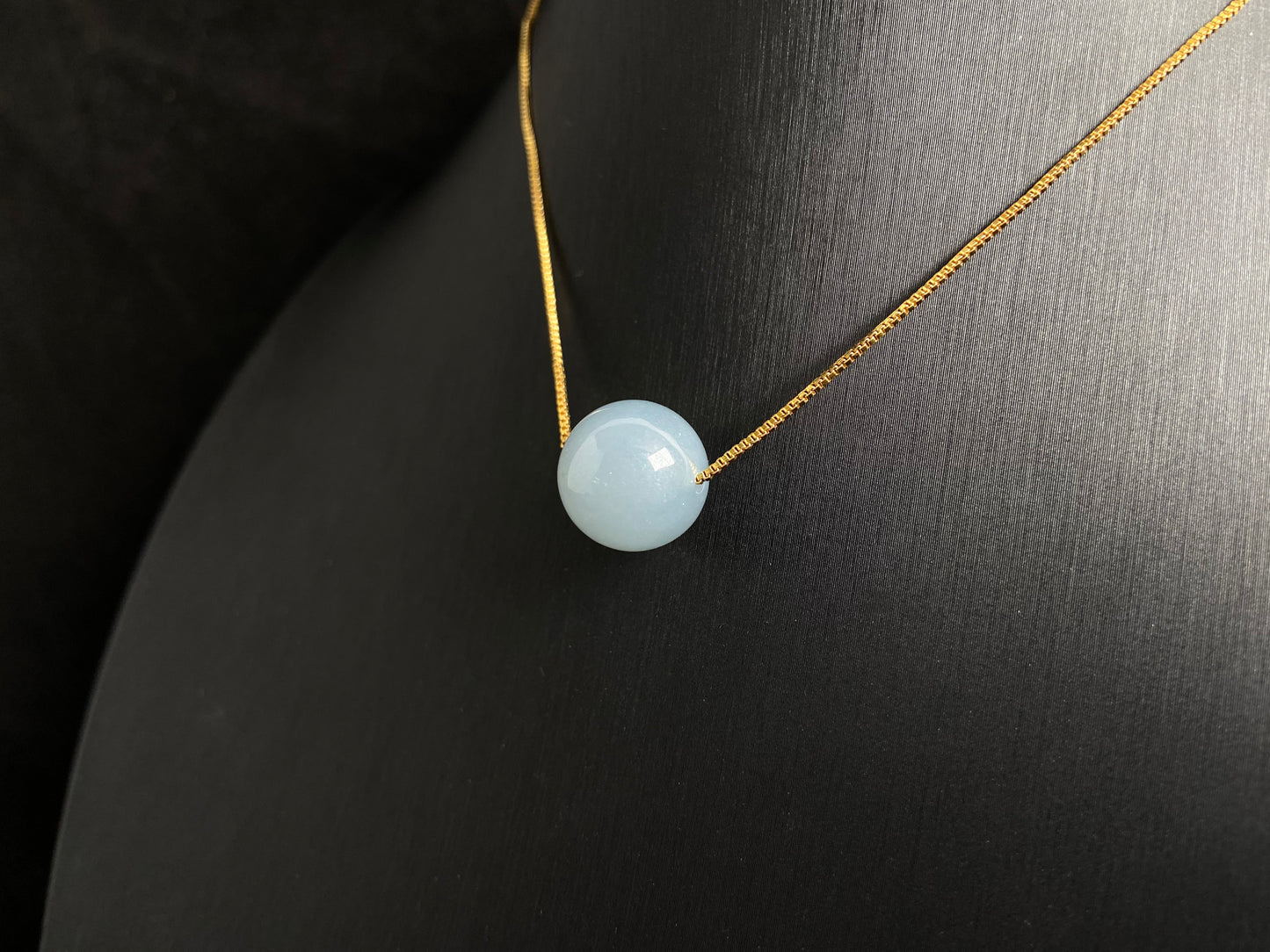 A single milky white jade bead pendant, smooth and luminous.