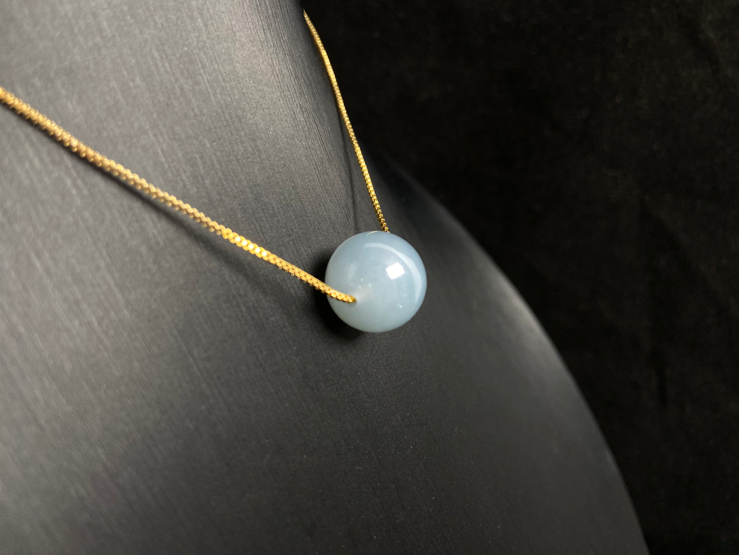 A single milky white jade bead pendant, smooth and luminous.