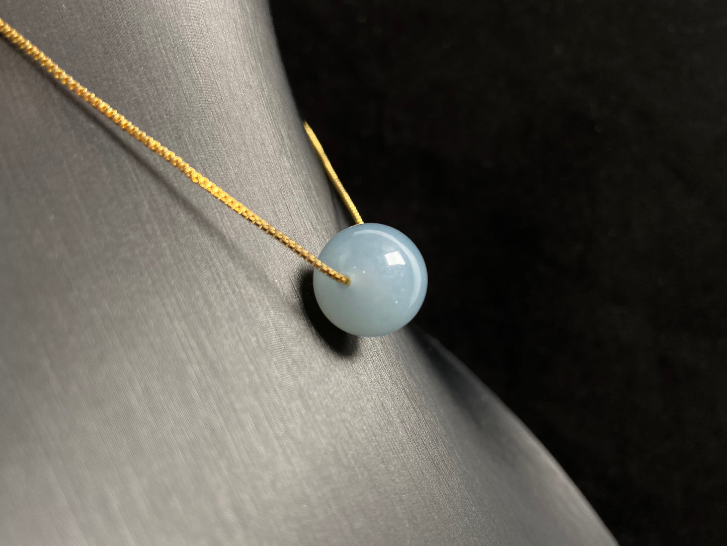 A single milky white jade bead pendant, smooth and luminous.