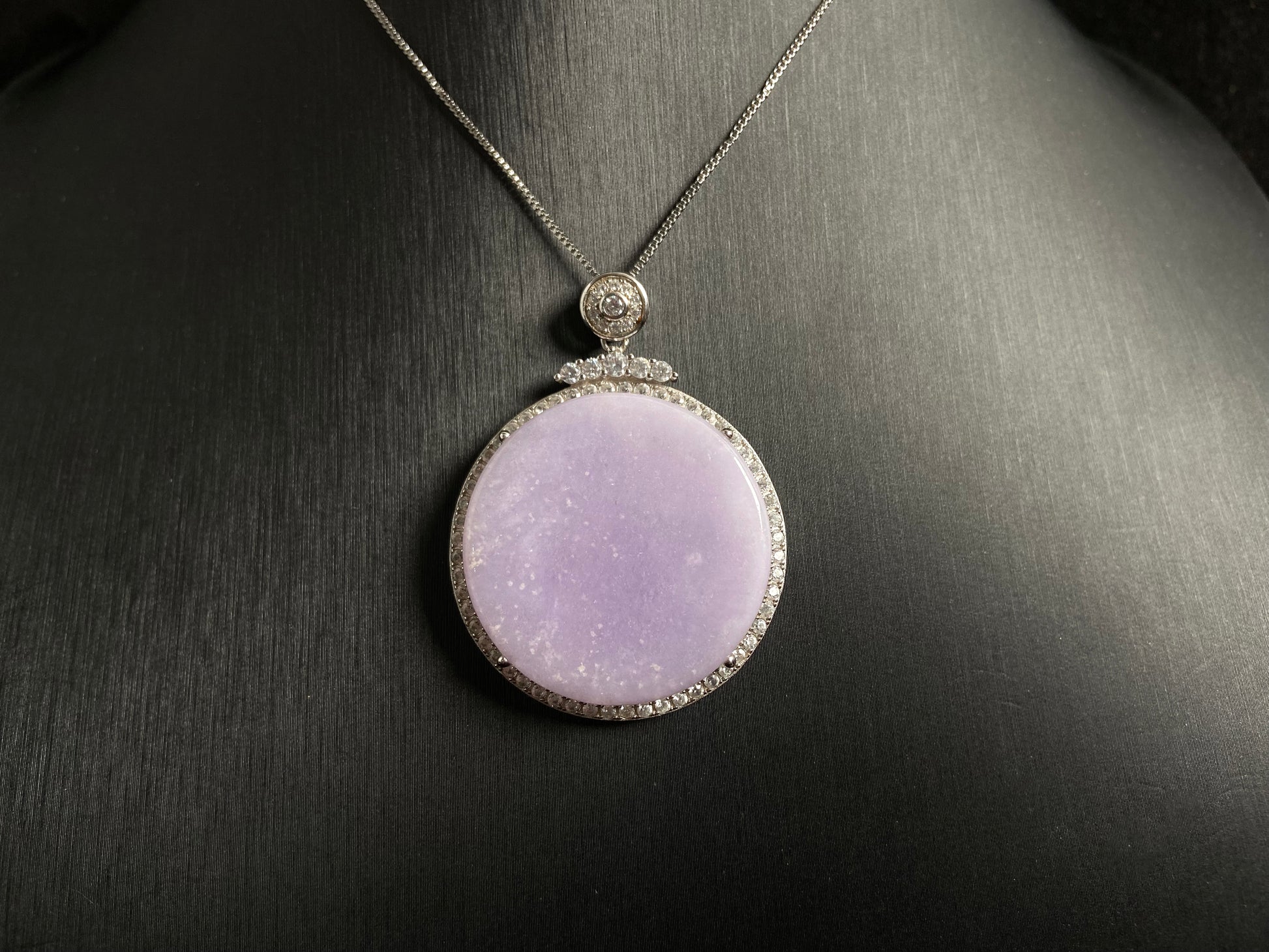 A circular purple jade pendant, elegantly framed in a 925 silver border.