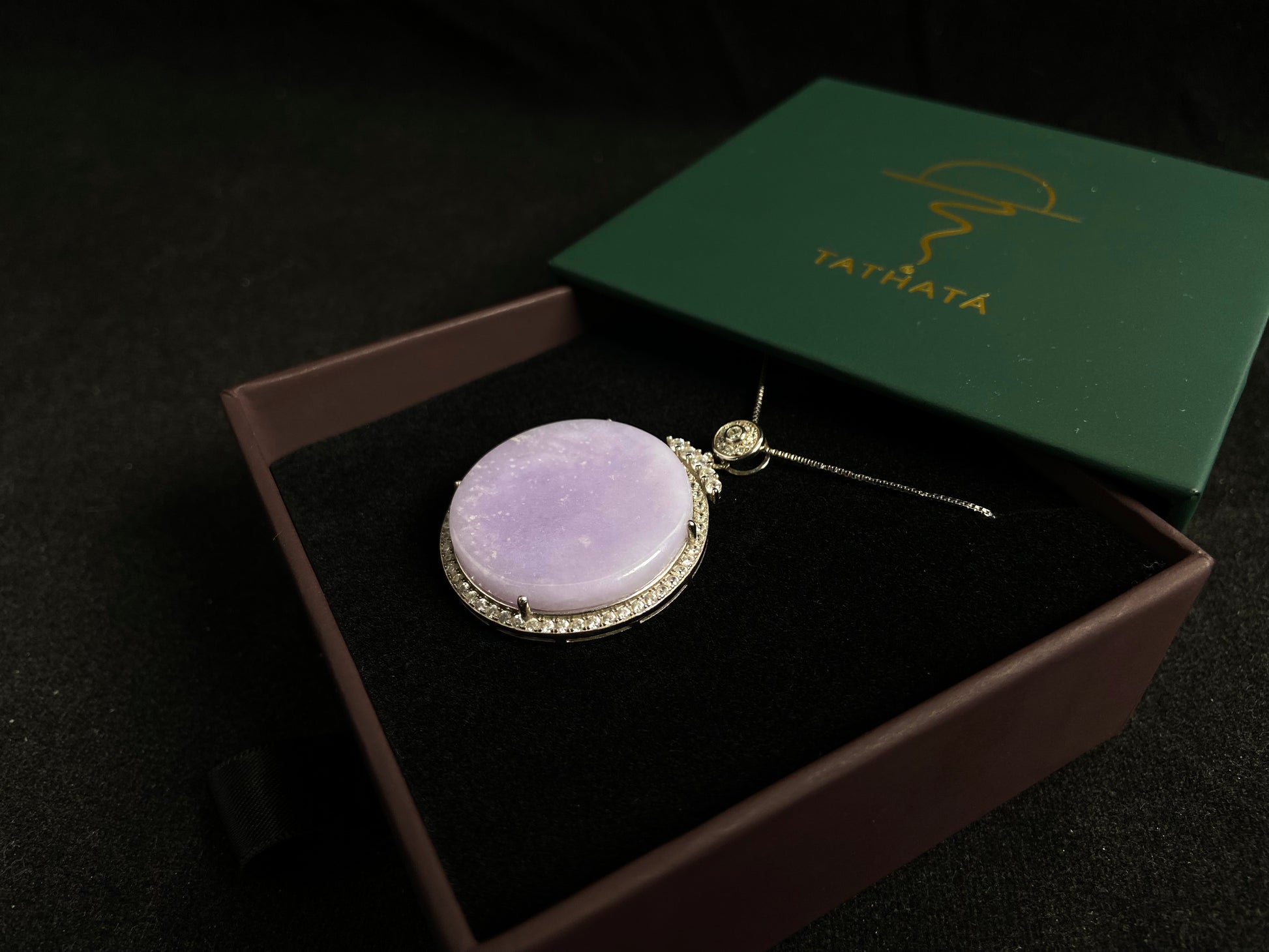 A circular purple jade pendant, elegantly framed in a 925 silver border.