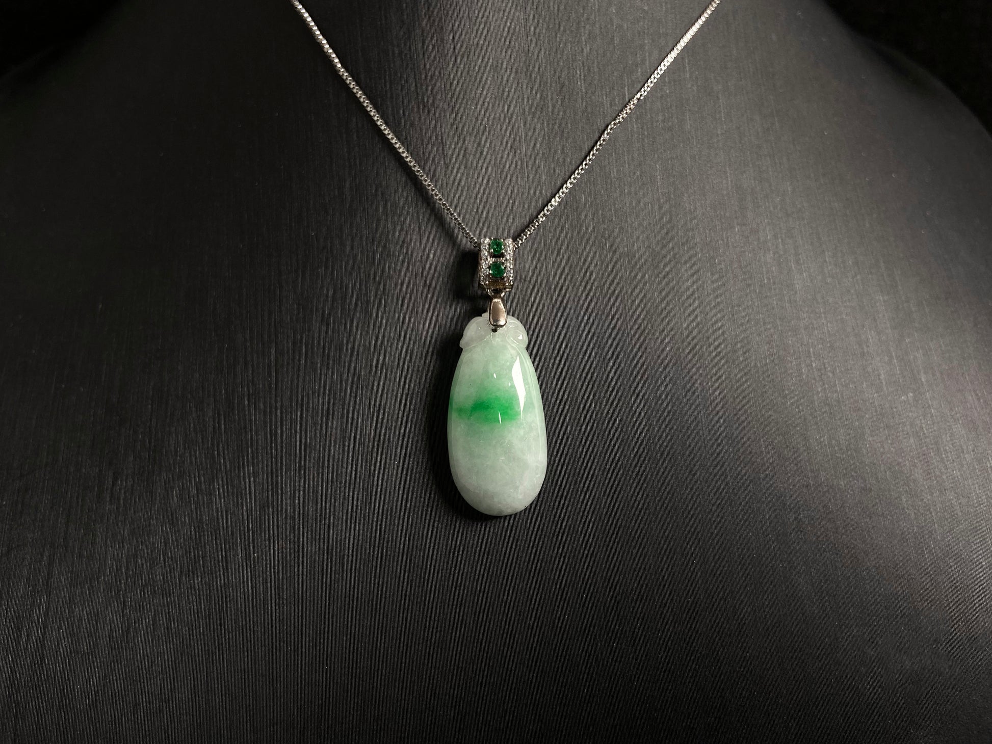 A "Fortune Melon" jade pendant featuring a white base adorned with a soft green accent.