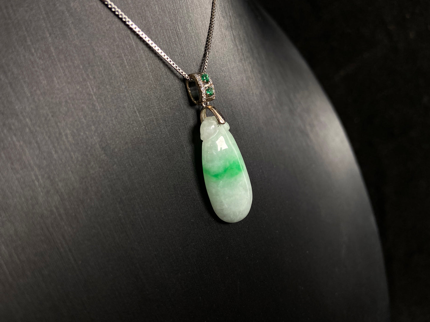 A "Fortune Melon" jade pendant featuring a white base adorned with a soft green accent.