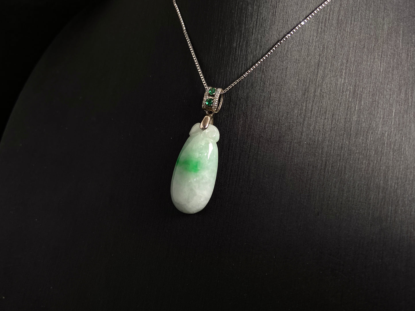 A "Fortune Melon" jade pendant featuring a white base adorned with a soft green accent.