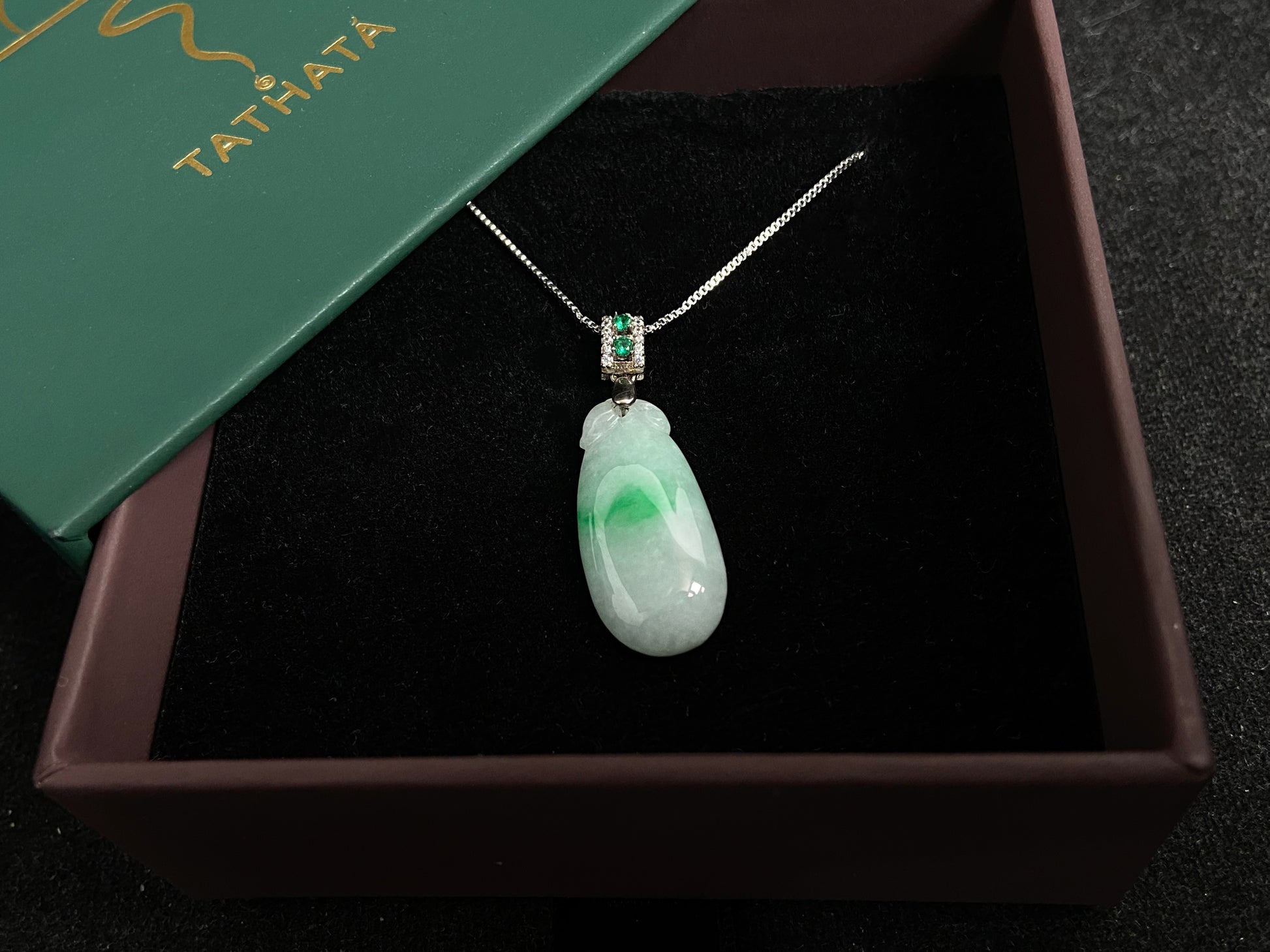 A "Fortune Melon" jade pendant featuring a white base adorned with a soft green accent.