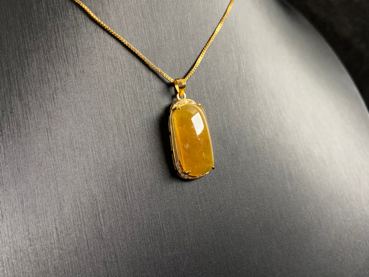 A golden yellow jade centerpiece, elegantly embraced by a gold plated 925 silver frame.