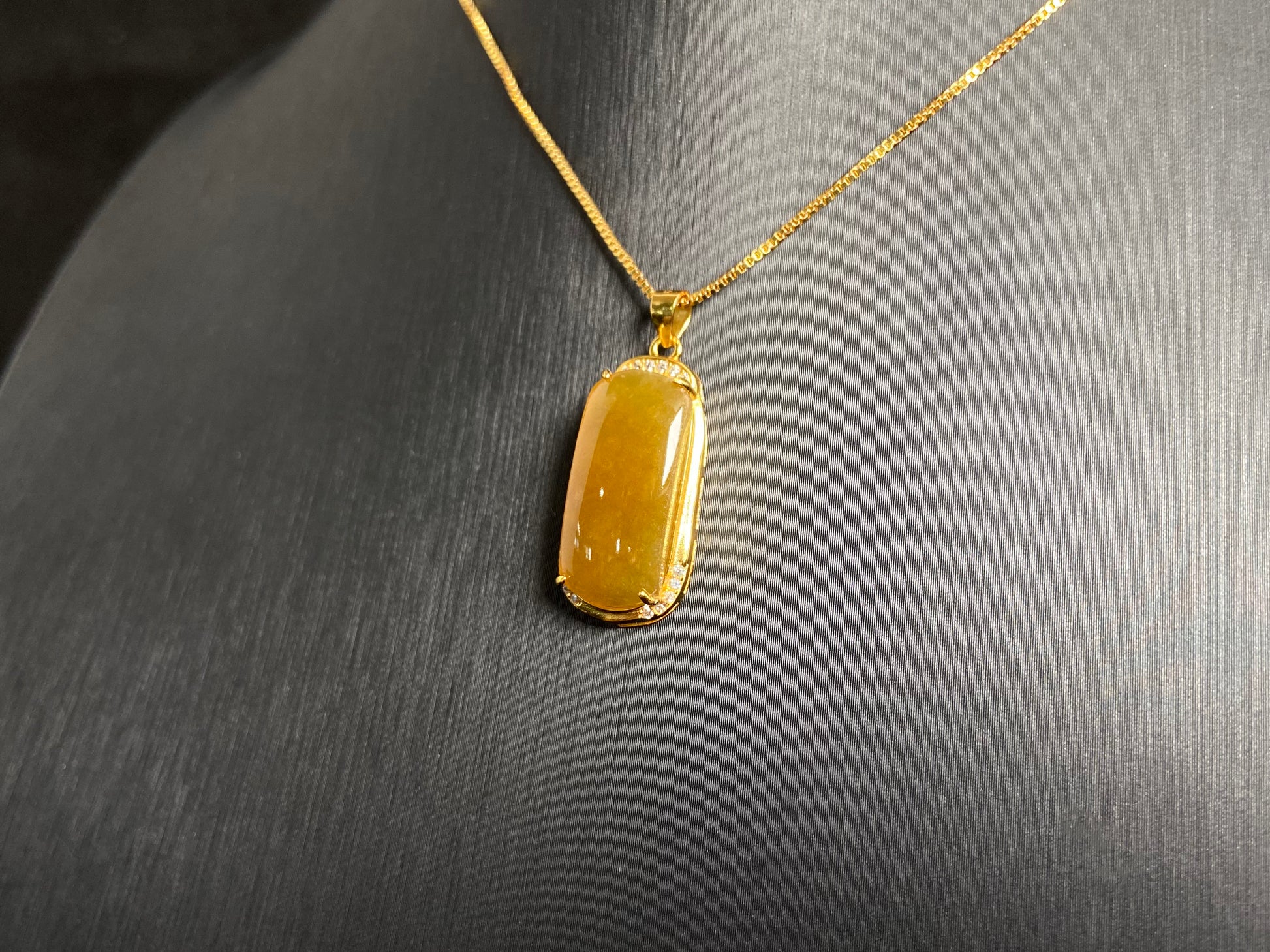 A golden yellow jade centerpiece, elegantly embraced by a gold plated 925 silver frame.