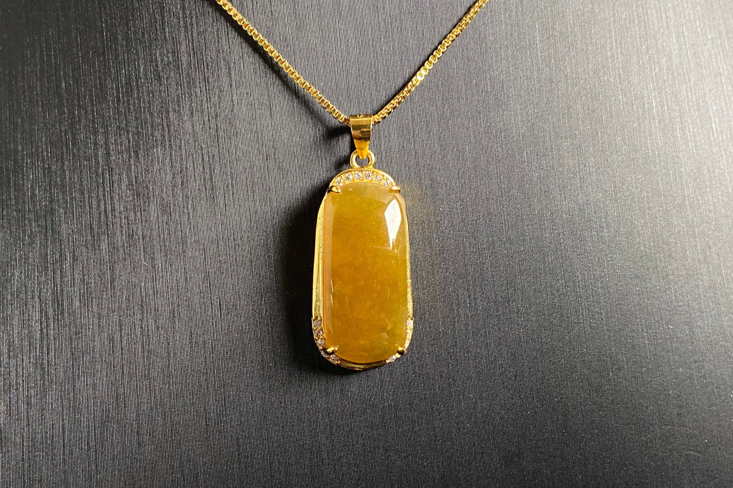 A golden yellow jade centerpiece, elegantly embraced by a gold plated 925 silver frame.