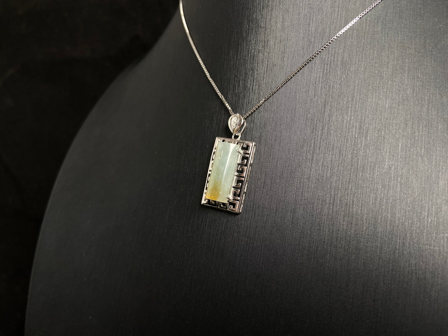 This unique jade pendant features a semi cylindrical column design with a subtle yellow accent floating at its base.