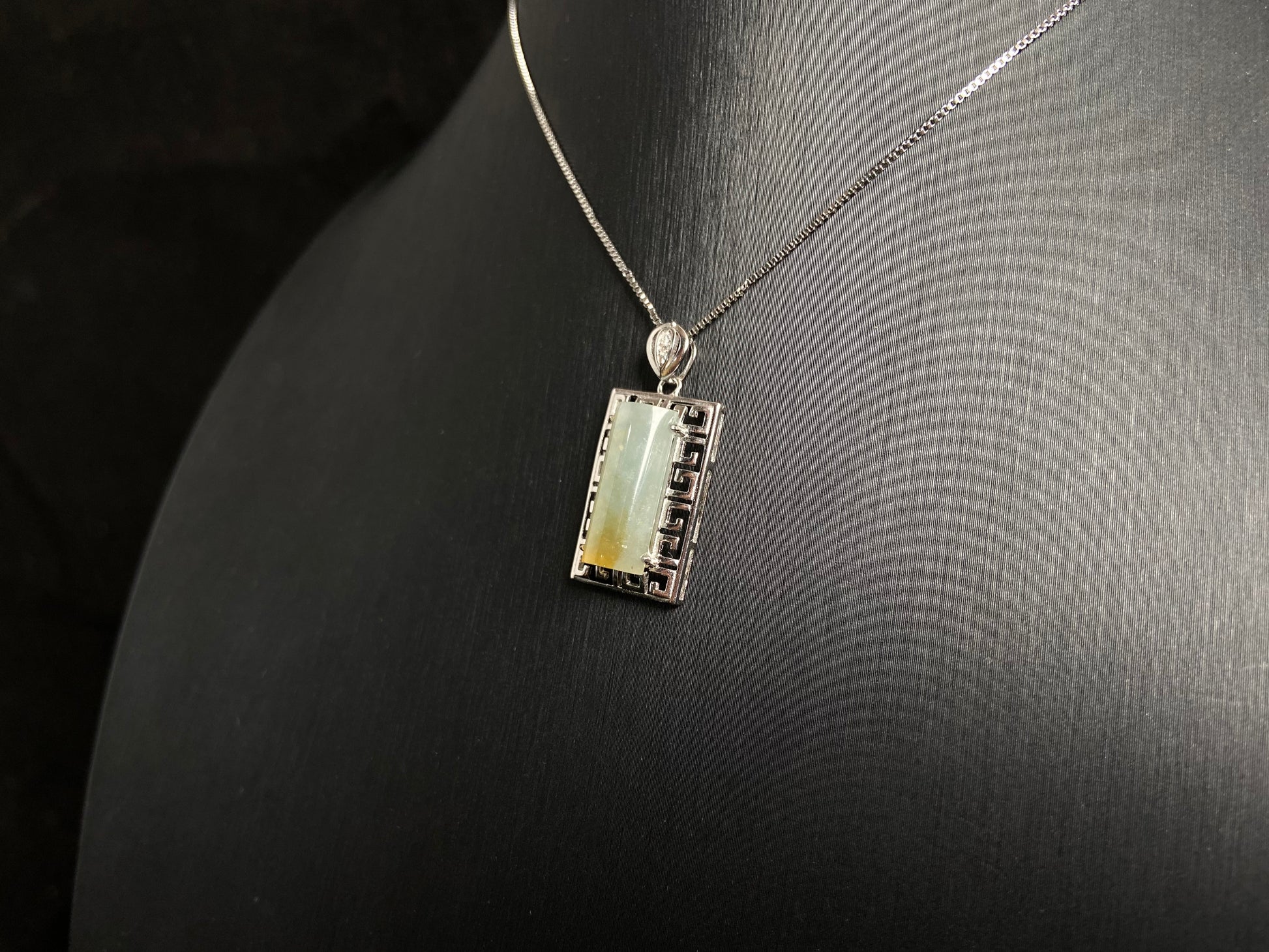 This unique jade pendant features a semi cylindrical column design with a subtle yellow accent floating at its base.