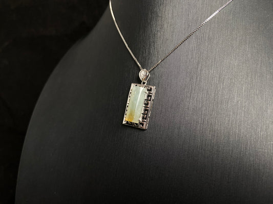 This unique jade pendant features a semi cylindrical column design with a subtle yellow accent floating at its base.