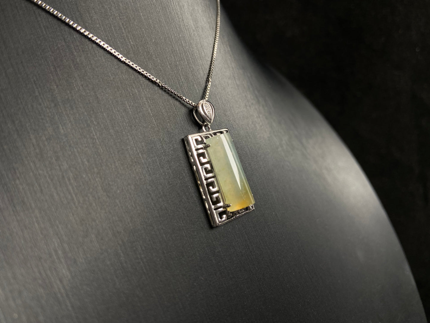 This unique jade pendant features a semi cylindrical column design with a subtle yellow accent floating at its base.