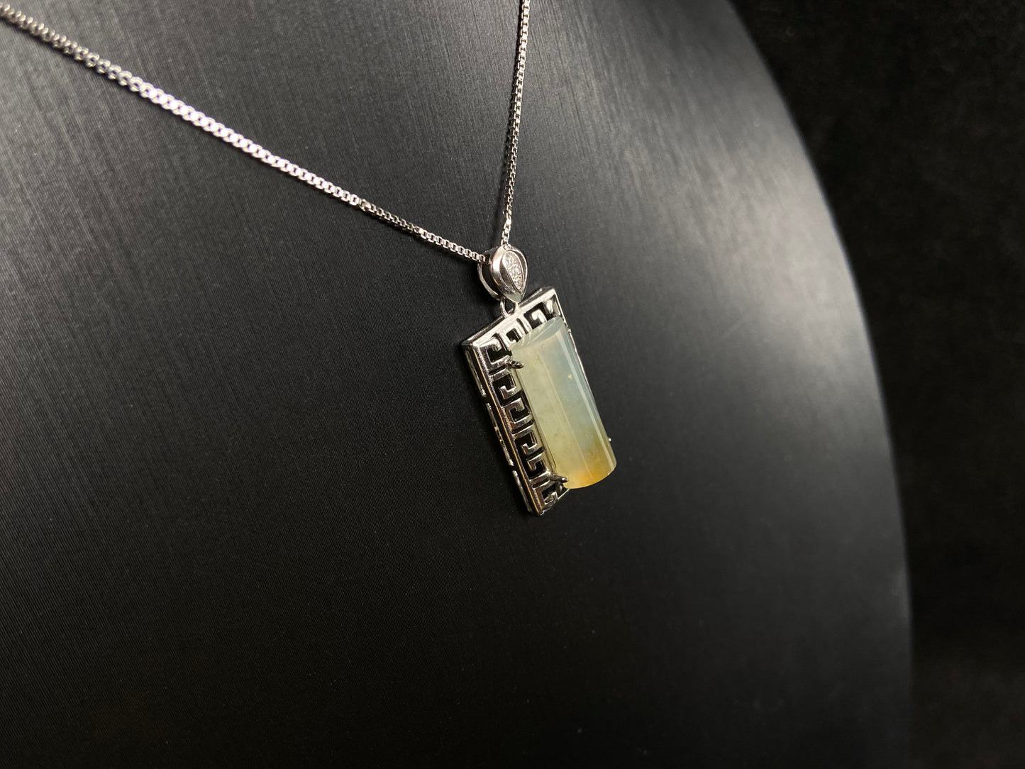 This unique jade pendant features a semi cylindrical column design with a subtle yellow accent floating at its base.