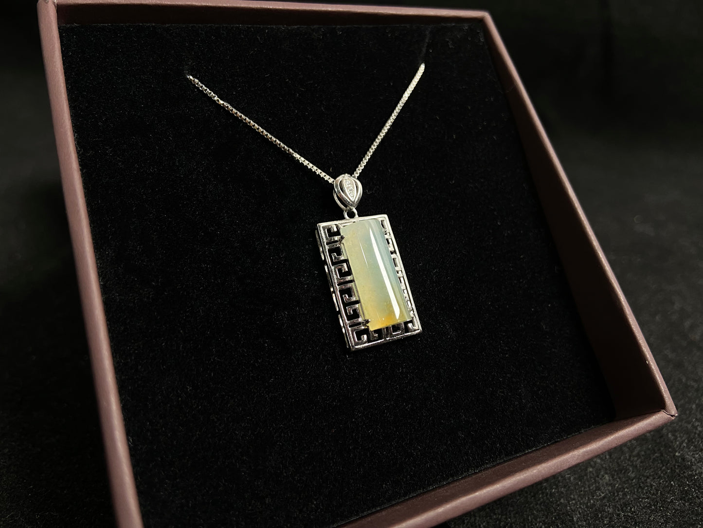 This unique jade pendant features a semi cylindrical column design with a subtle yellow accent floating at its base.