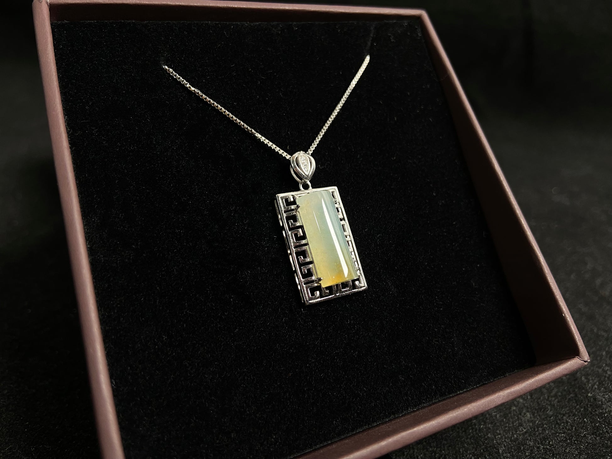 This unique jade pendant features a semi cylindrical column design with a subtle yellow accent floating at its base.