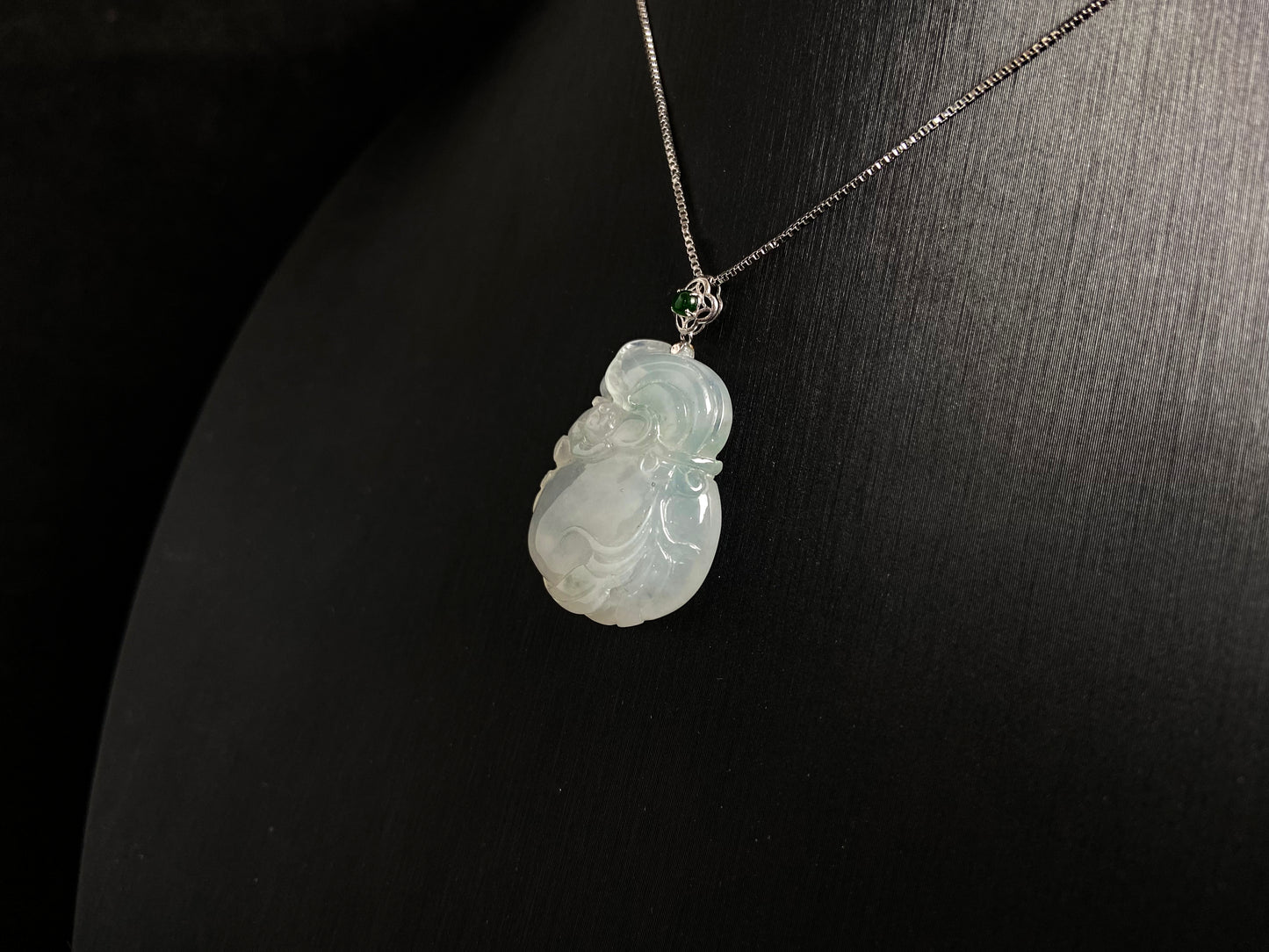 An icy jade fortune pouch pendant with floating green accents.