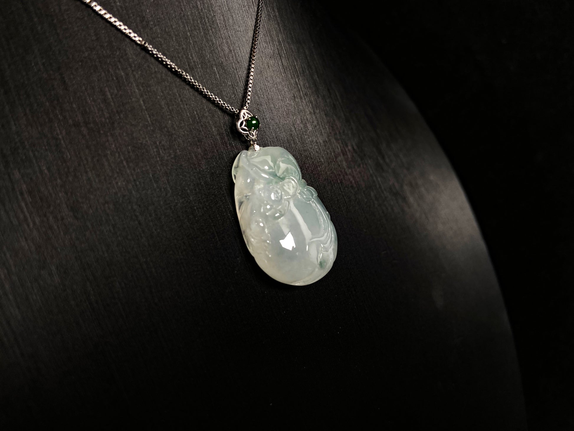 An icy jade fortune pouch pendant with floating green accents.