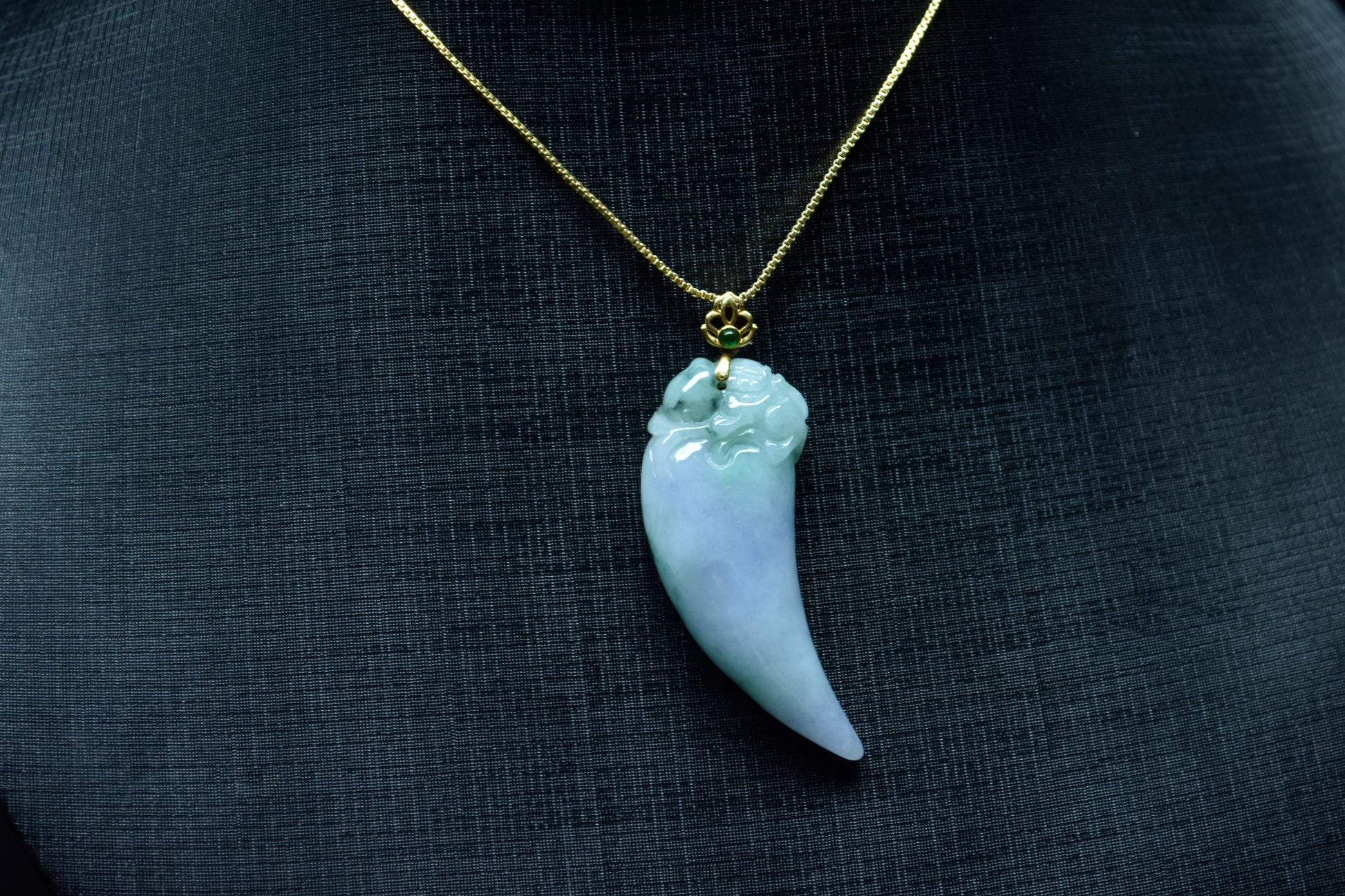 This jadeite pendant features a shark tooth shape in white, purple, and green.