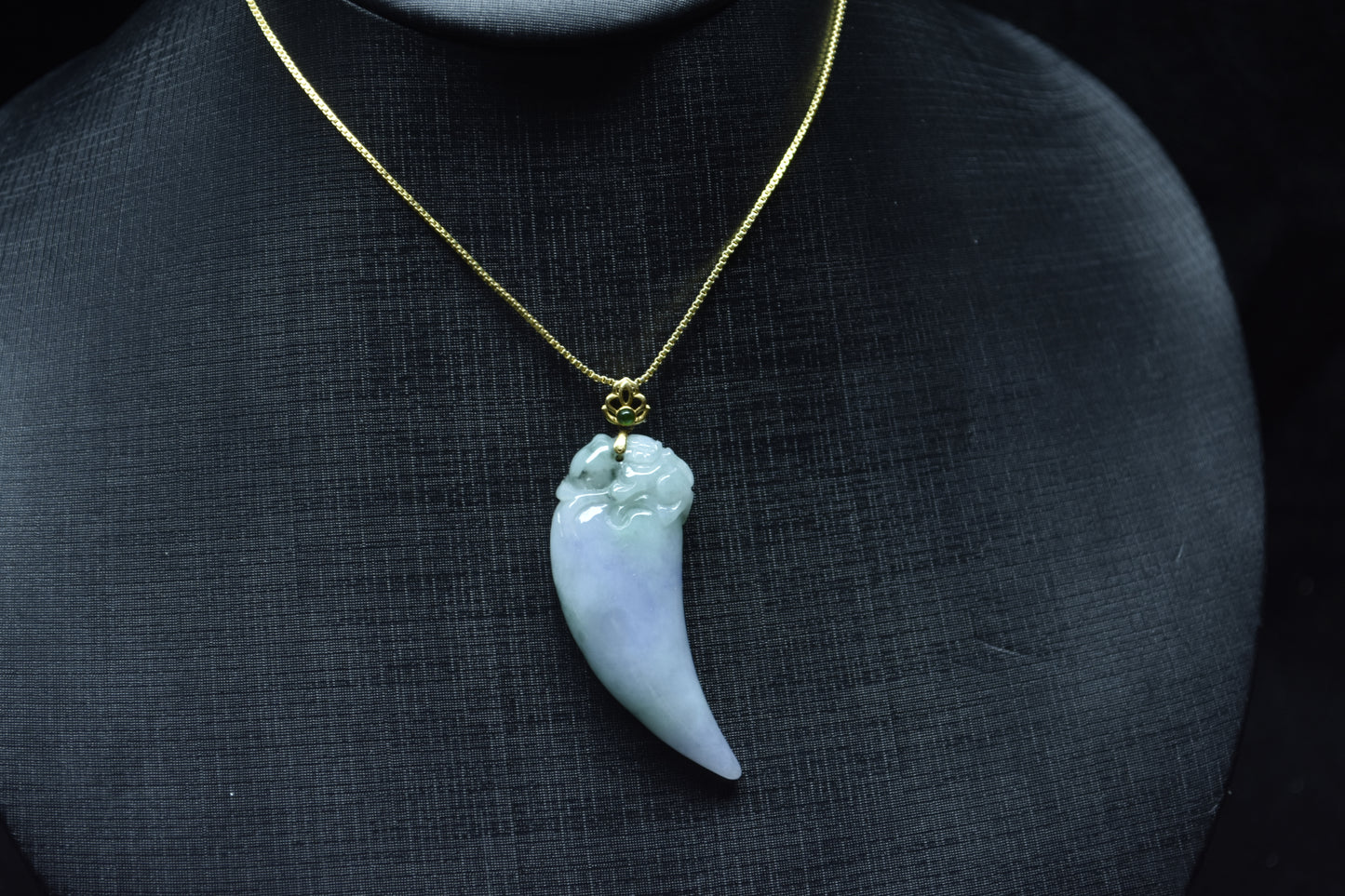 This jadeite pendant features a shark tooth shape in white, purple, and green.