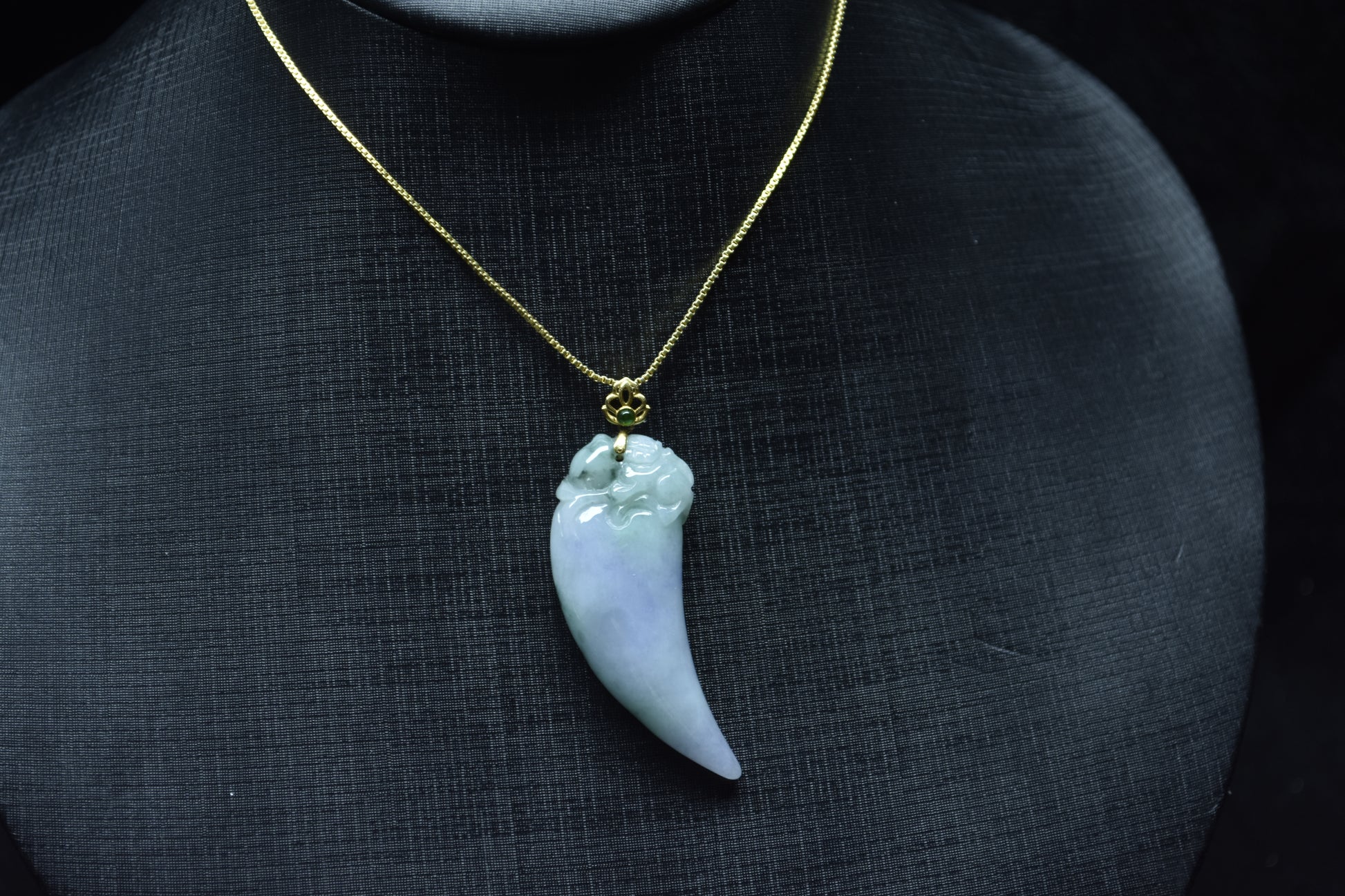 This jadeite pendant features a shark tooth shape in white, purple, and green.