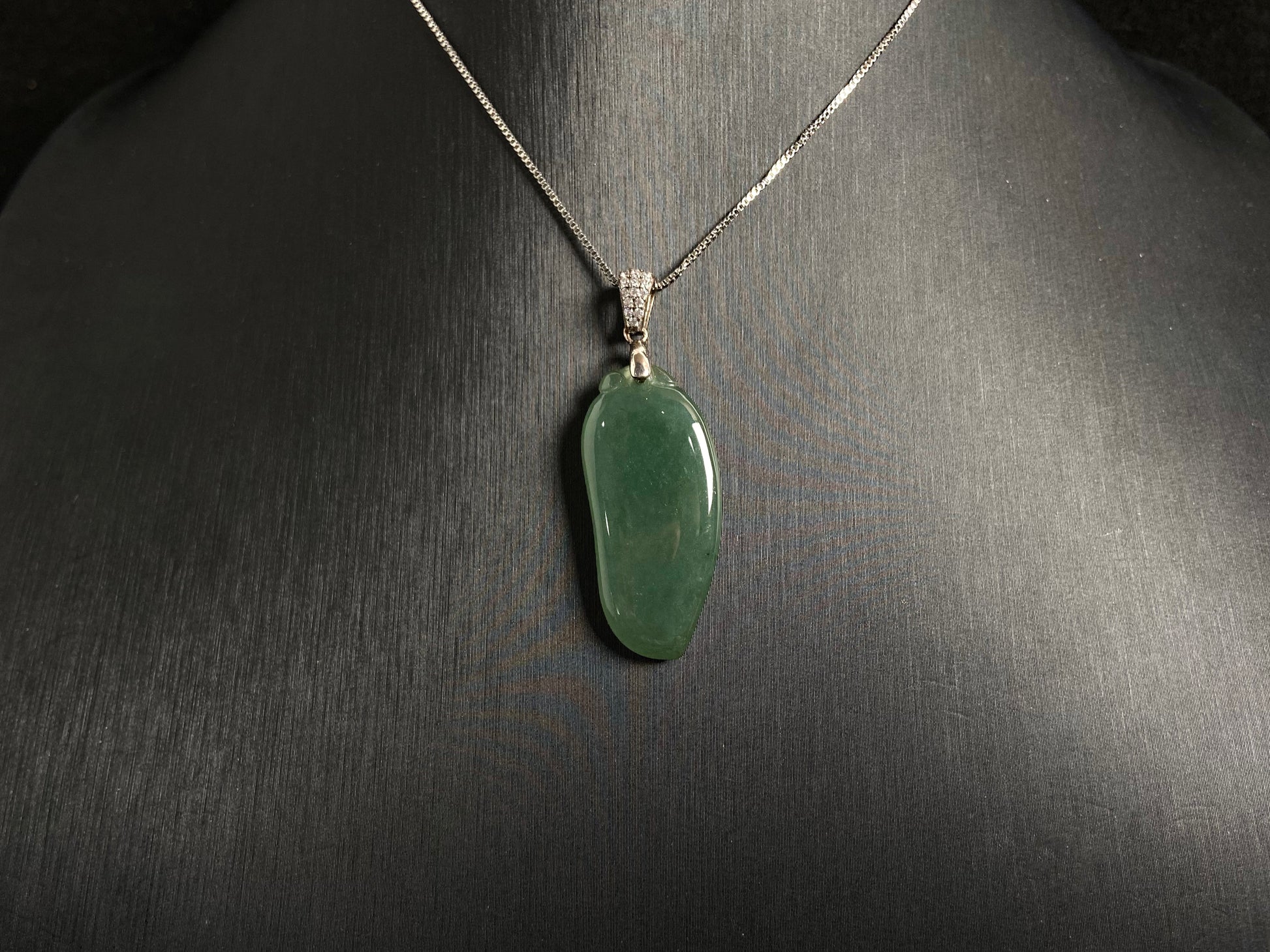 A deep green jade "Fortune Melon" pendant, symbolizing abundance and blessings.