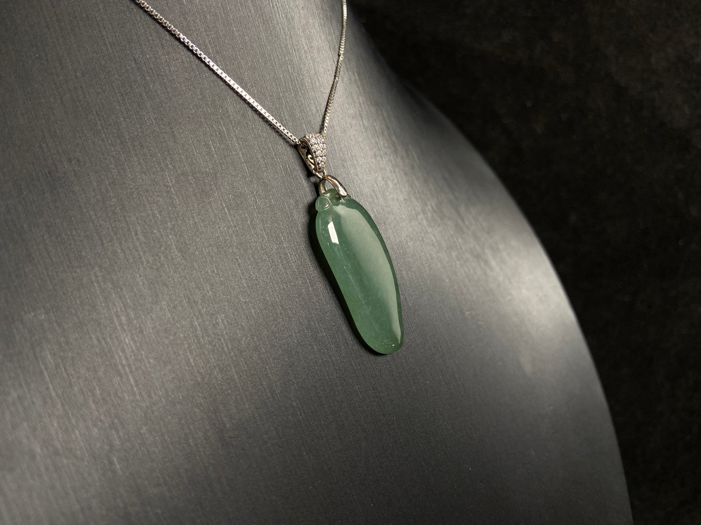 A deep green jade "Fortune Melon" pendant, symbolizing abundance and blessings.