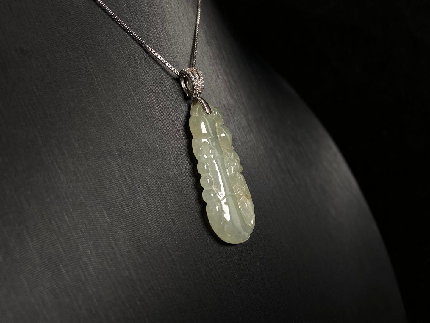 A translucent white jade bamboo pendant with a subtle golden glow.