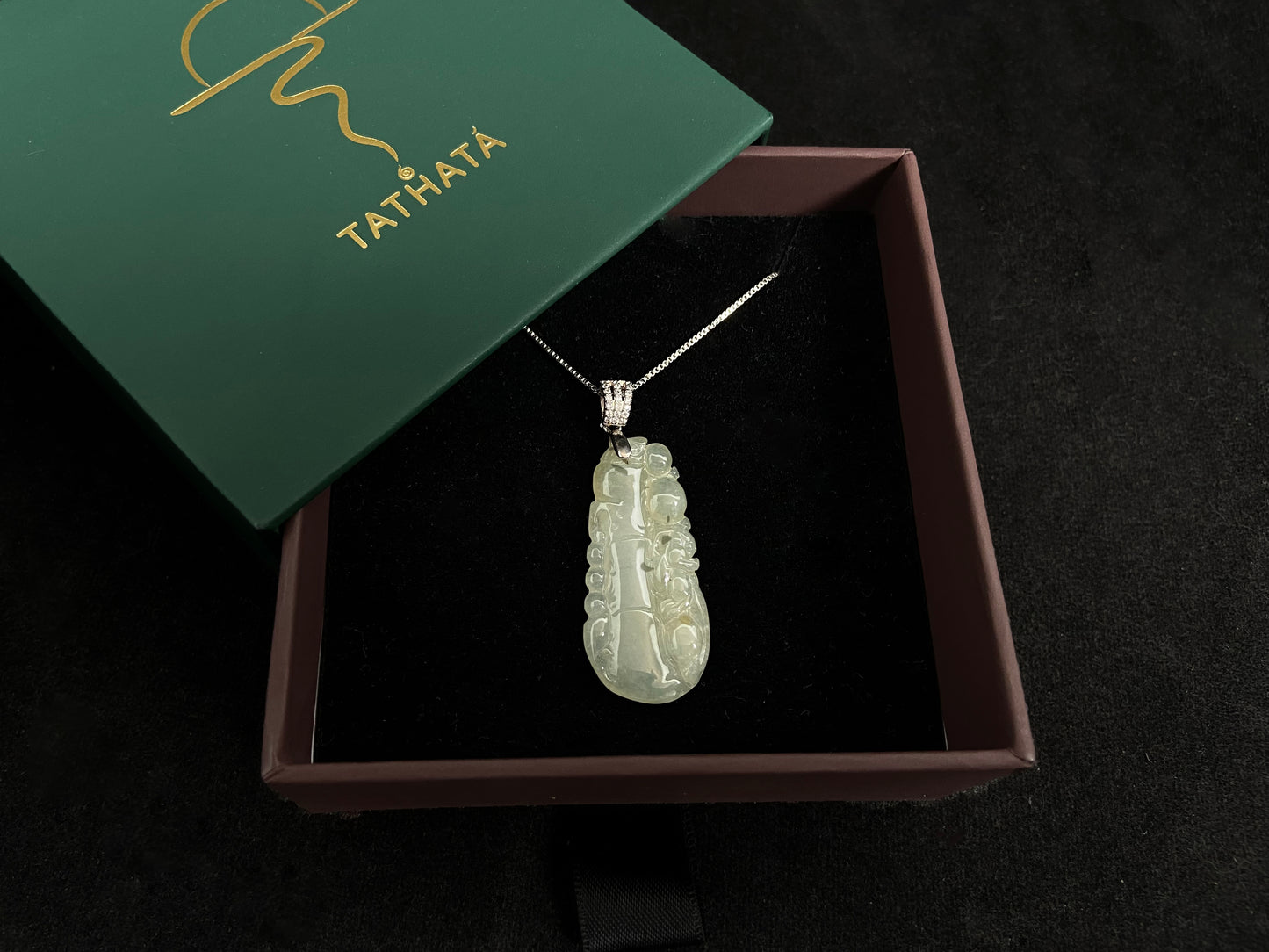 A translucent white jade bamboo pendant with a subtle golden glow.