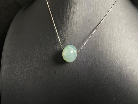 A pale green jade bead with a natural dark green accent.