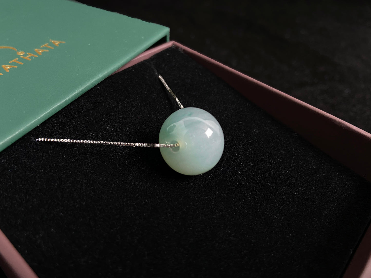 A pale green jade bead with a natural dark green accent.