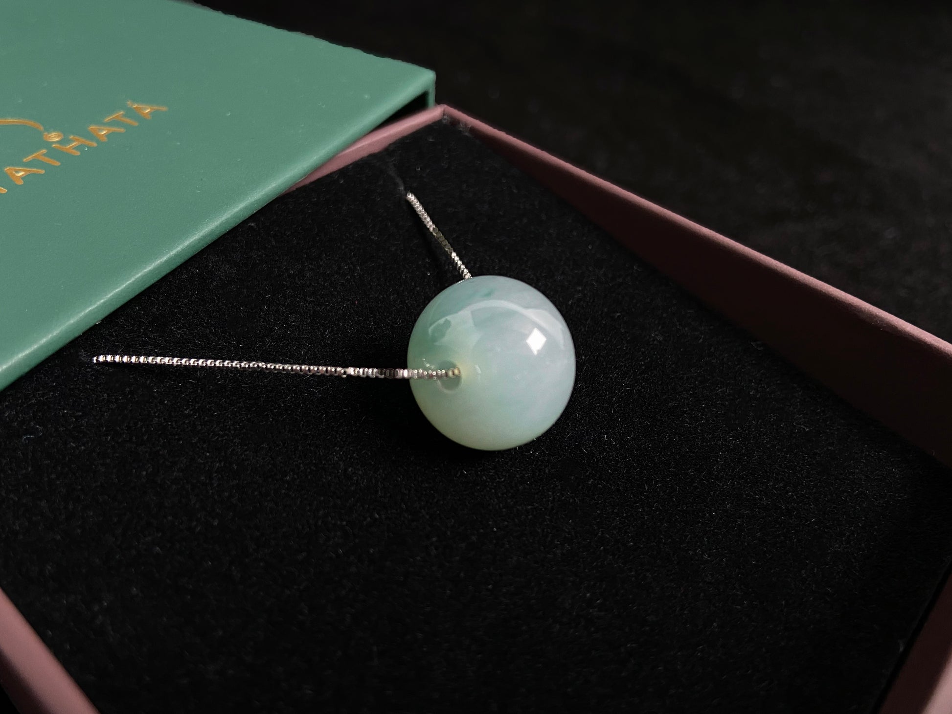A pale green jade bead with a natural dark green accent.