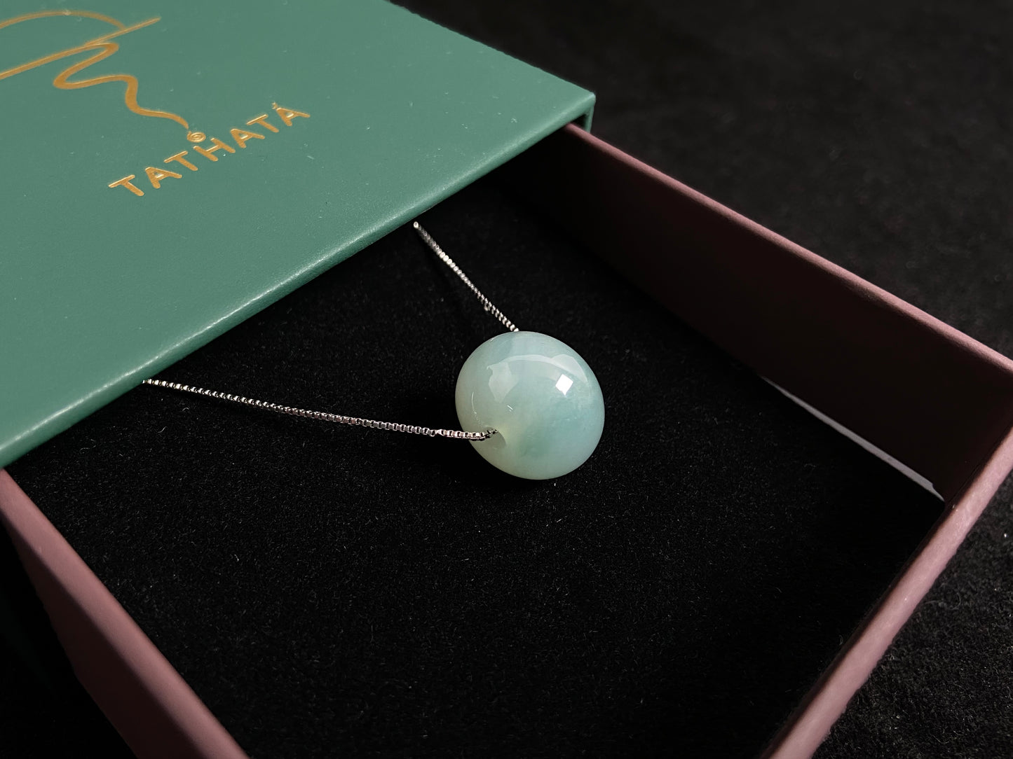 A pale green jade bead with a natural dark green accent.