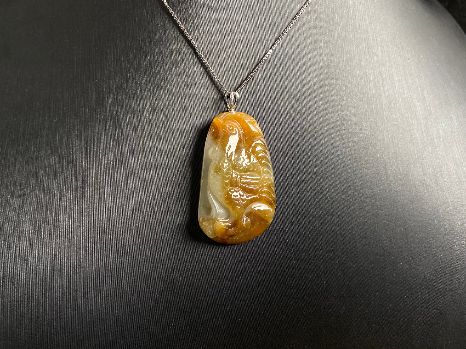This jade pendant features a phoenix design in warm brown tones with subtle white accents, symbolizing nobility and good fortune.