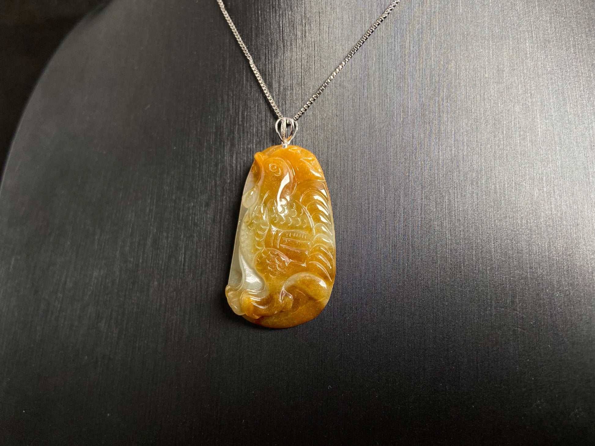 This jade pendant features a phoenix design in warm brown tones with subtle white accents, symbolizing nobility and good fortune.