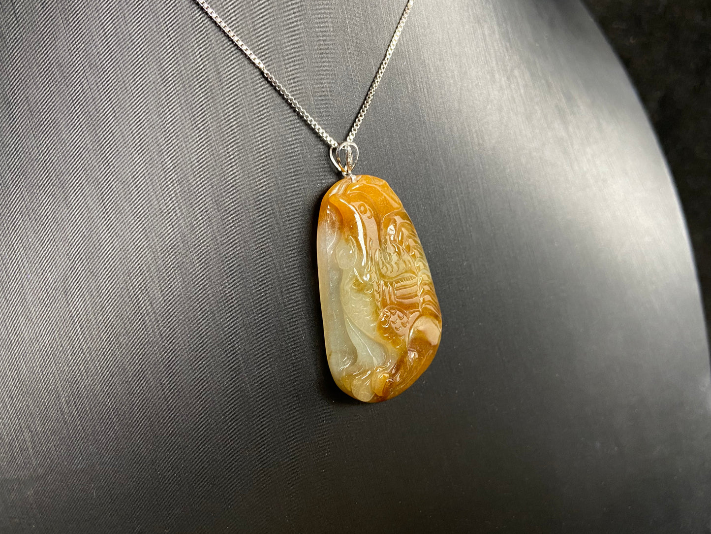 This jade pendant features a phoenix design in warm brown tones with subtle white accents, symbolizing nobility and good fortune.